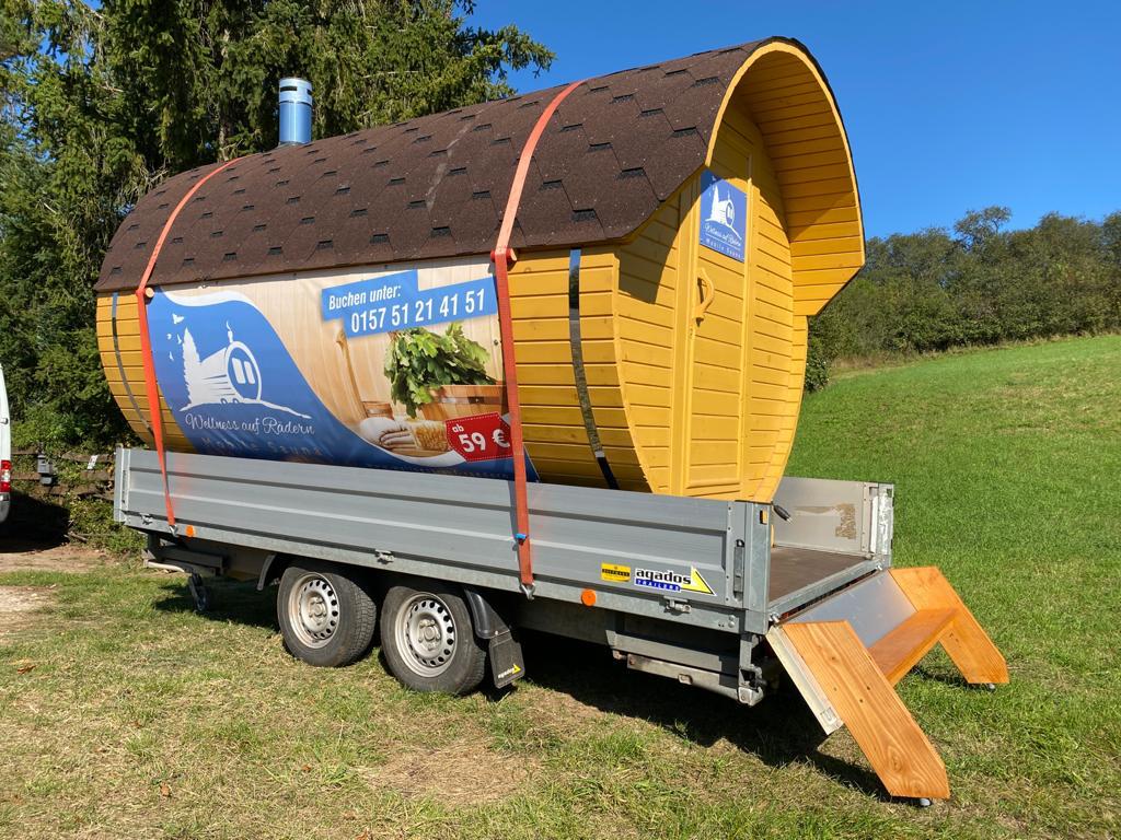 Mobile Fass-Sauna von Wellness auf Rädern auf einer sonnigen Wiese